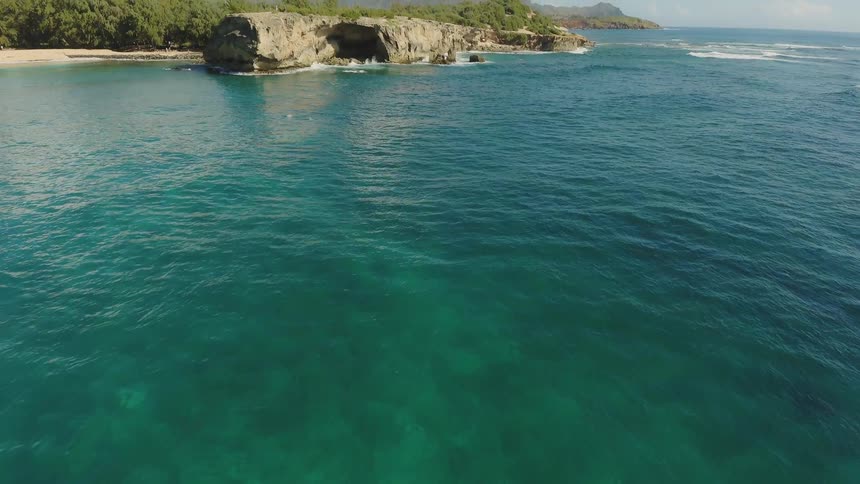 The tide flows towards the cliff lined shore
