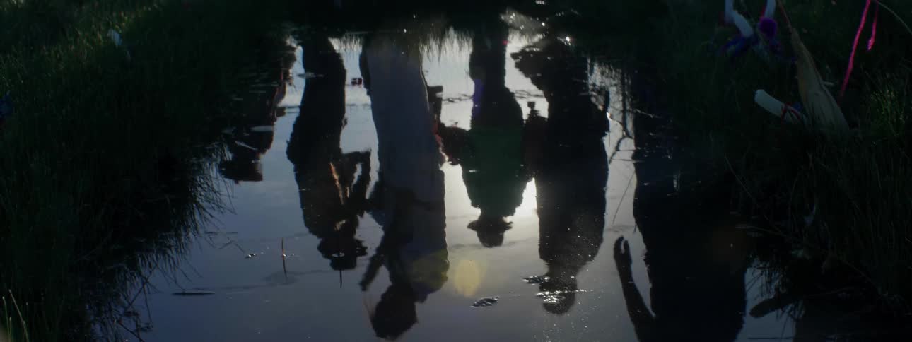 People reflected in a pool of water with sun shining