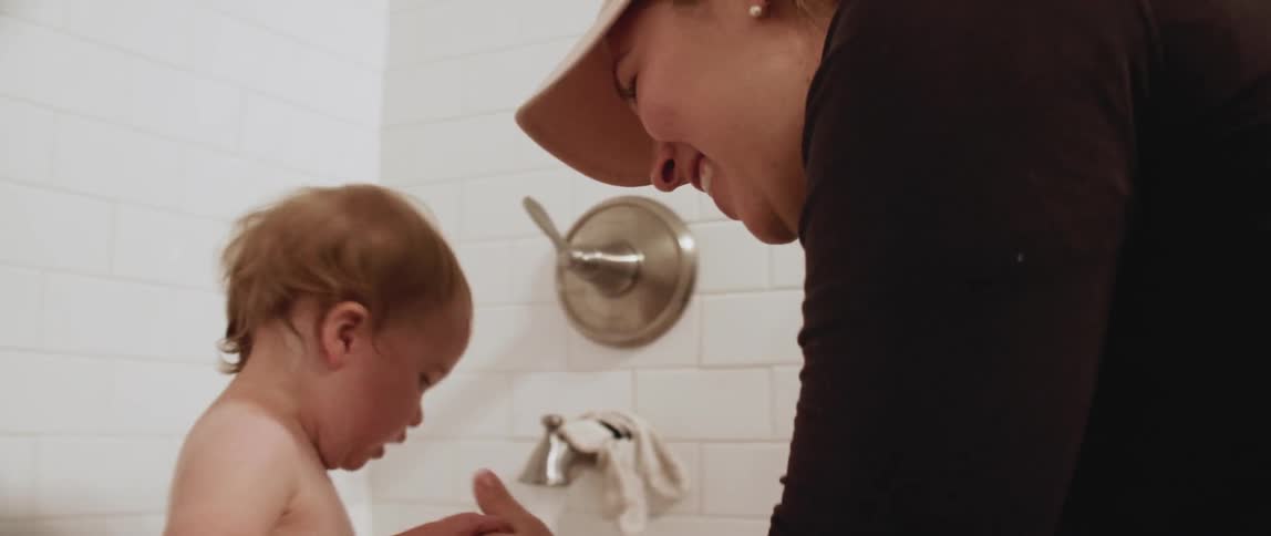 Woman washes a toddler in a bathtub
