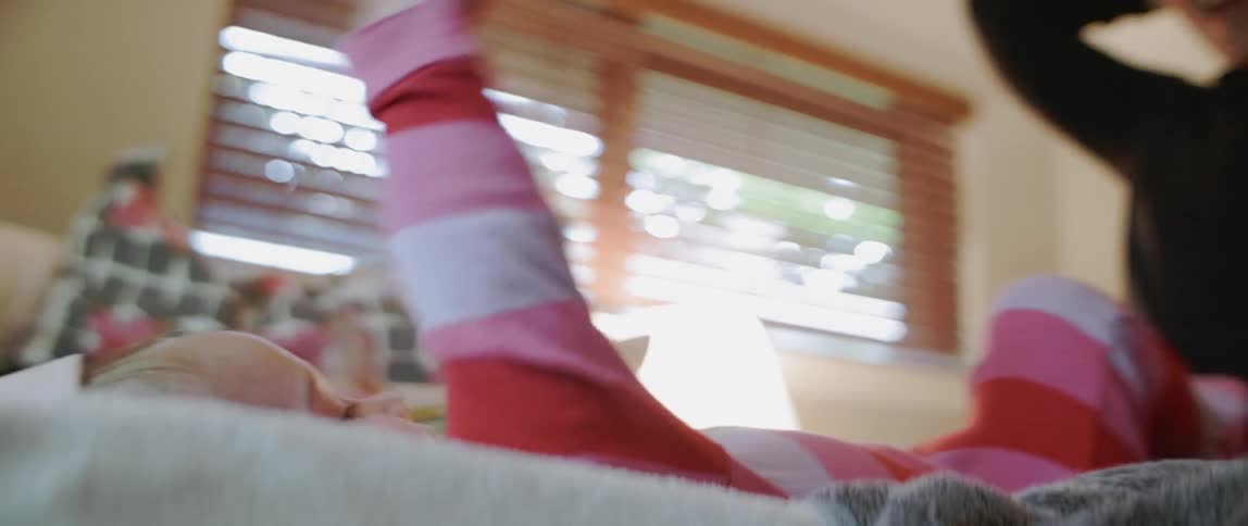 A baby claps and grabs his feet while lying down