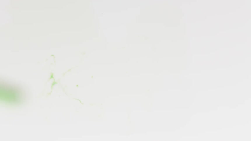Green liquid drops into a pool of white liquid