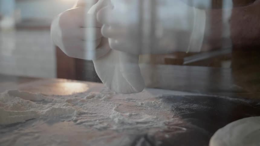 A person is forming dough on the table