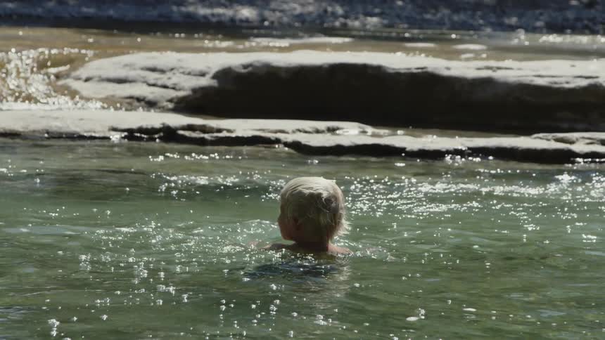 The child is playing in the creek water