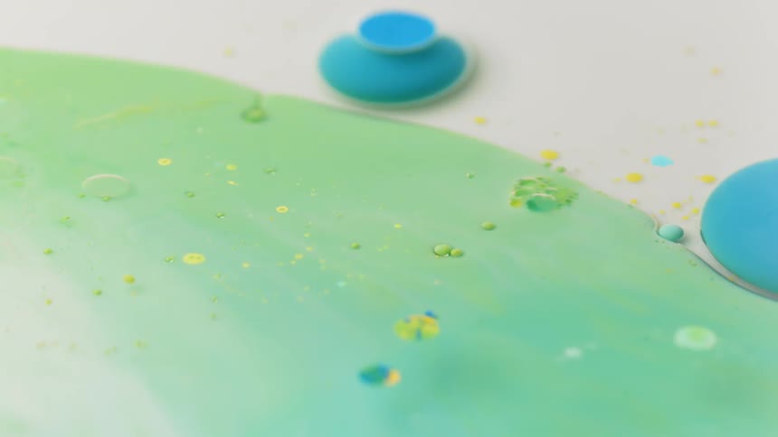 A circle of blue paint pushes into a green blob