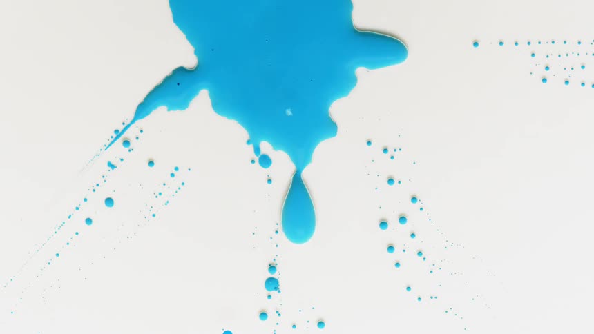 A blob of blue liquid is contracting back into itself across a white surface