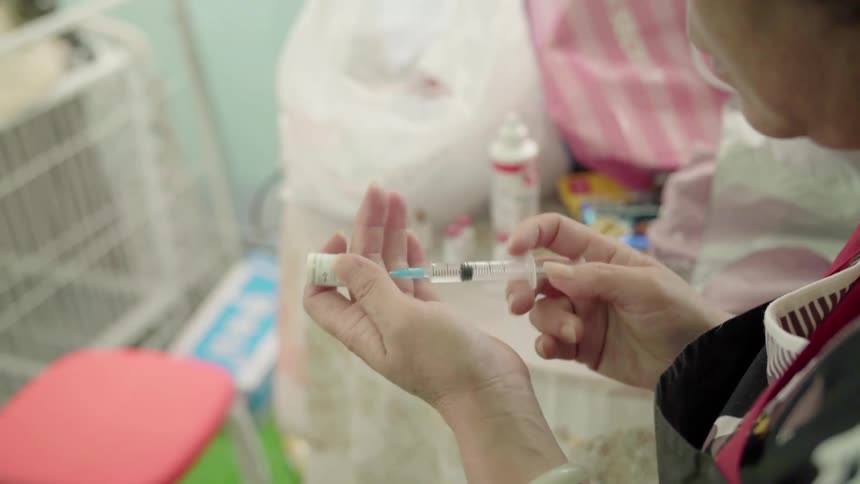 Woman plunging a needle into a vial