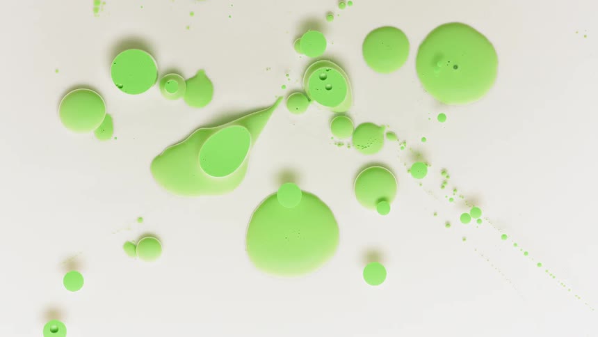Circles and blobs of green paint stretch and form in liquid