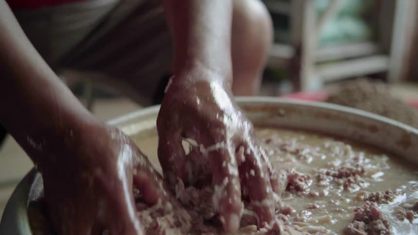Woman stirs and squishes a pot of goop with her hands