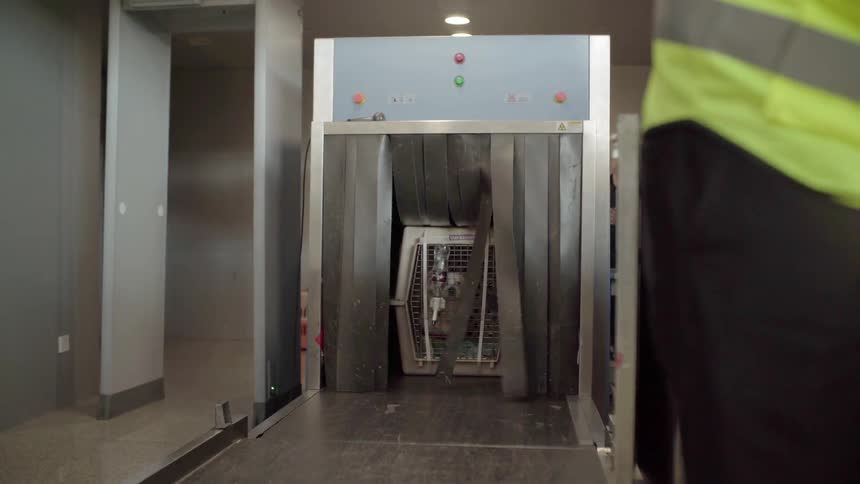 A dog in a pet carrier goes through the security check at an airport