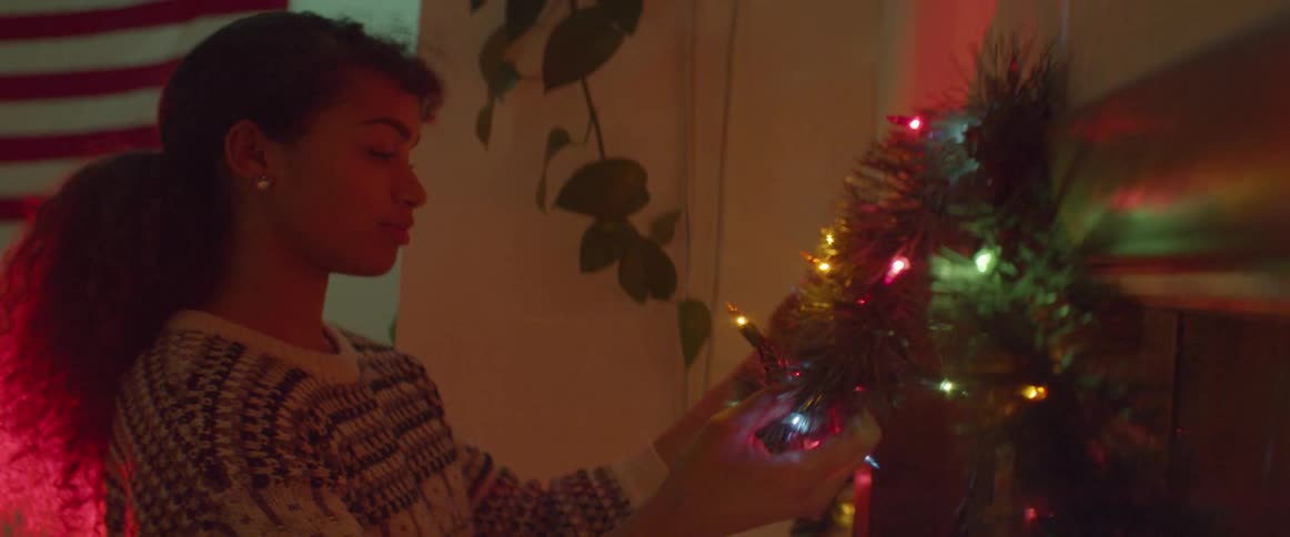 A woman hangs christmas lights and garland