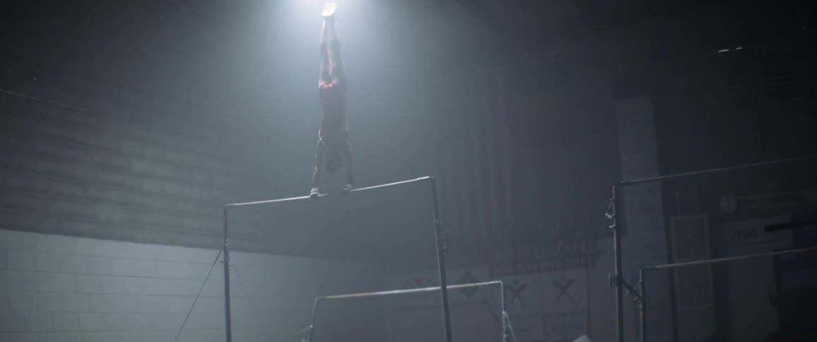 The woman is spinning around the bar in the gym
