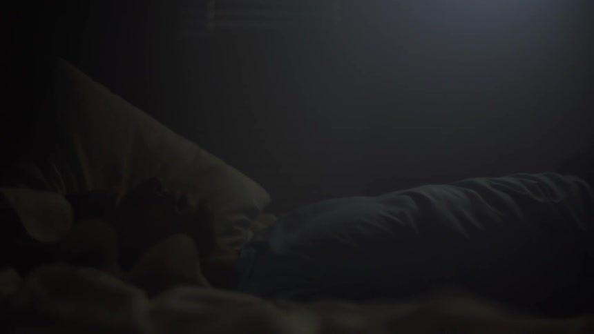 Man falls onto bed in dark room in slow motion