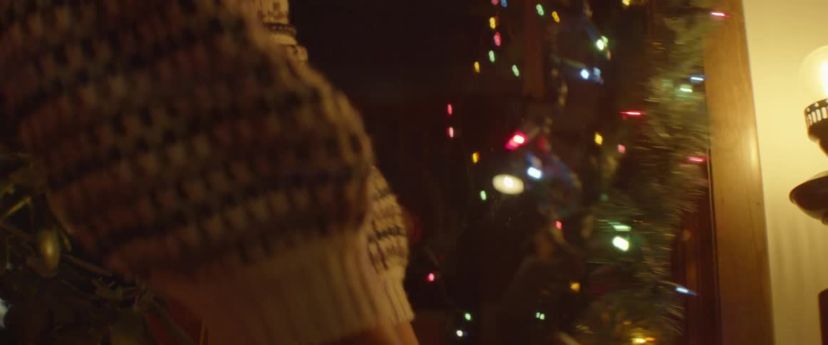 A woman hangs christmas lights and garland indoors