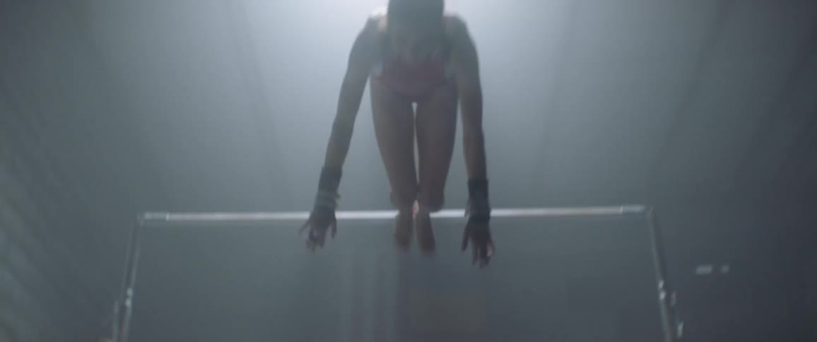The woman jumps off the bar landing after doing a flip