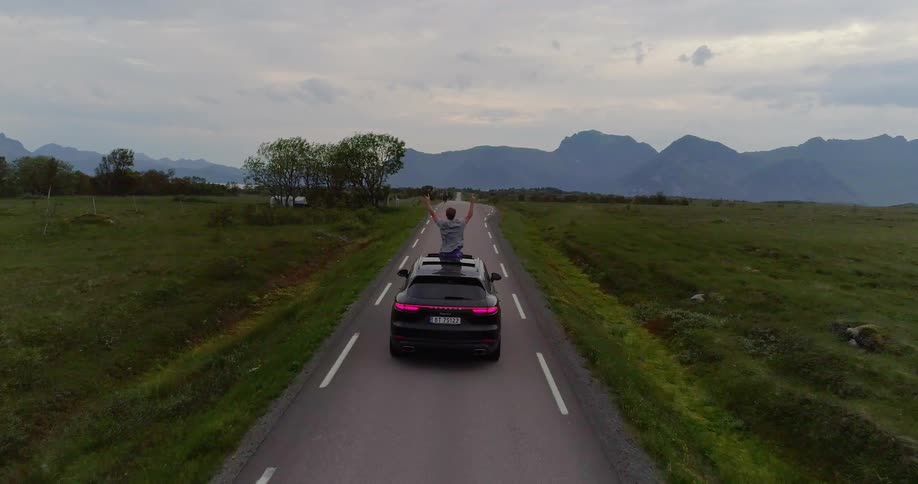 Person riding in a car through the country sticking out of the sunroof