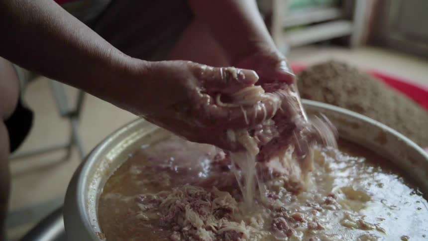 A person shreds meat with their hands