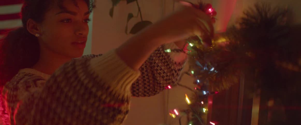 Woman hanging up multicolored lights indoors at night