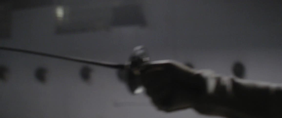 A person is fencing in a gym moving back and forth