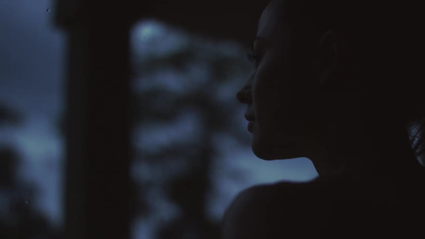 Woman stands near trees at night