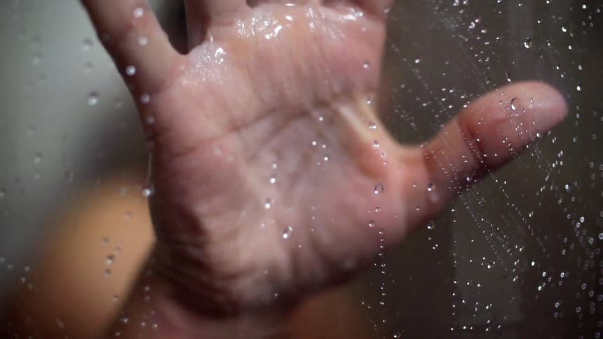 Someone placing their palm against glass that had water running down it