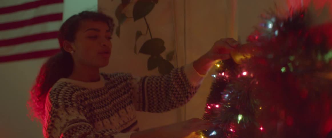 Woman reaches to hang colored lights around a window