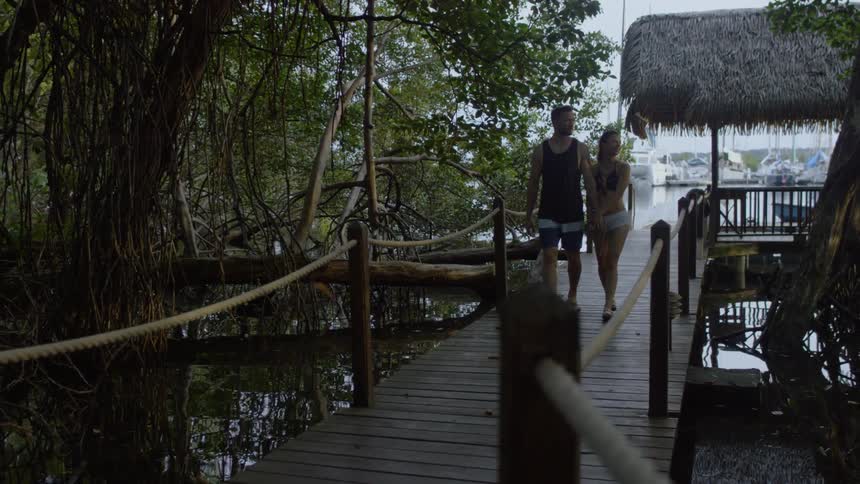 A man and woman walk down a dock by the water
