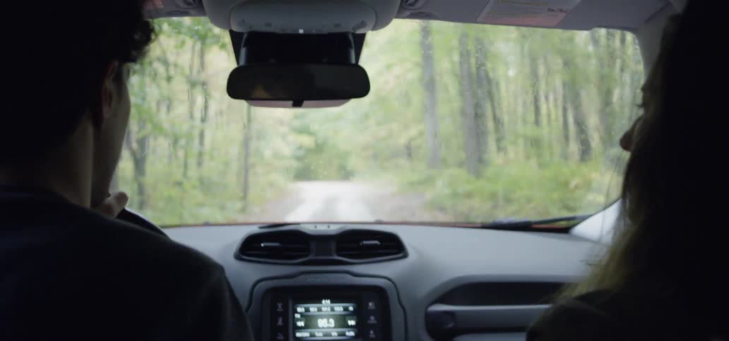 Man and woman in a vehicle driving through the woods