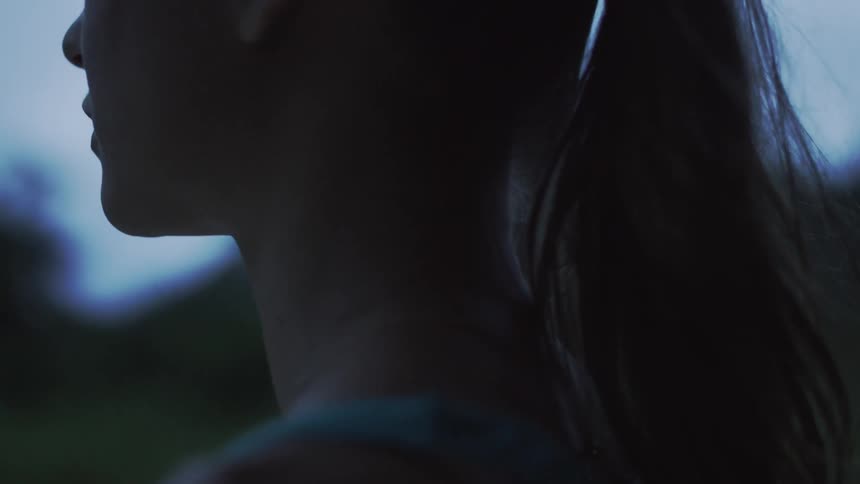 A woman stands outside at dusk