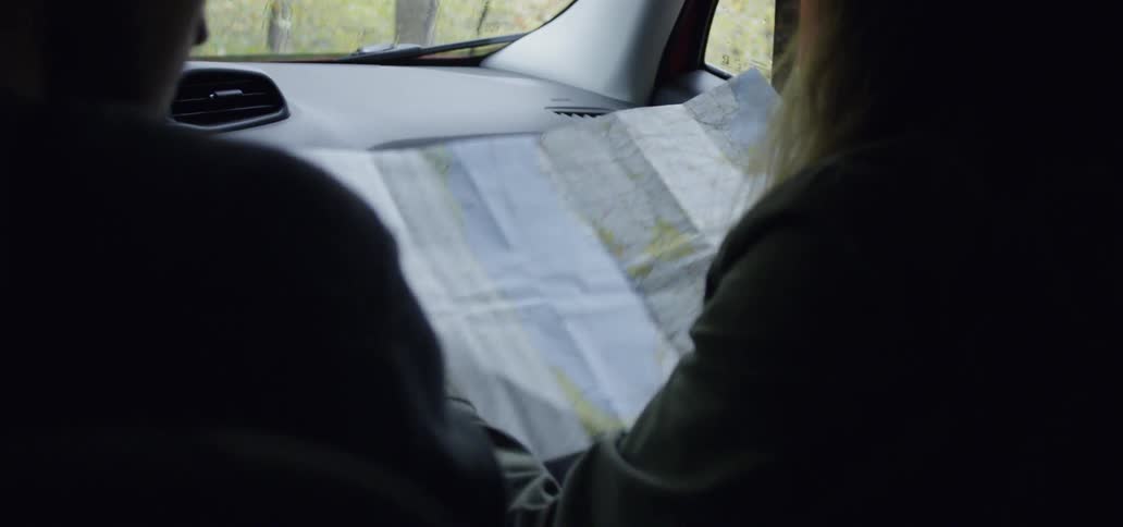 Man and woman look at a map while sitting in a vehicle