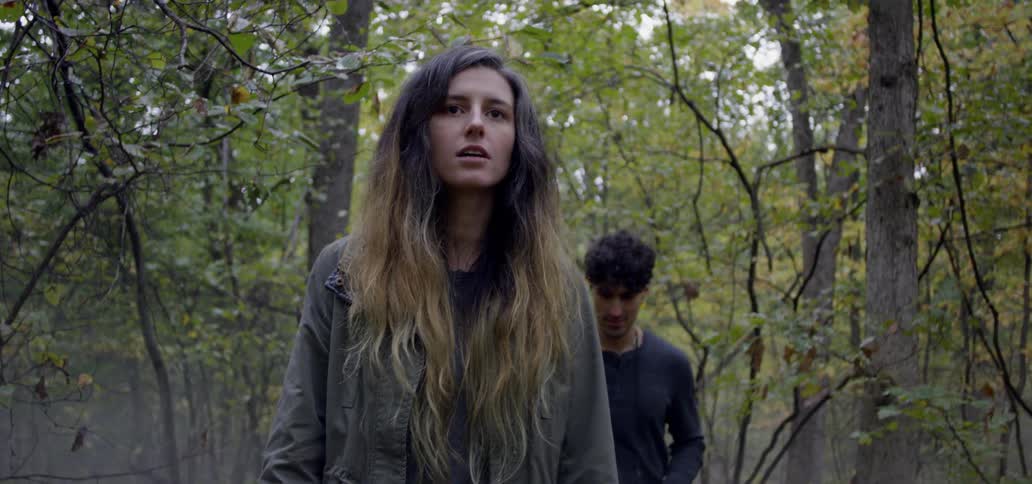 A man and woman hike in a forest