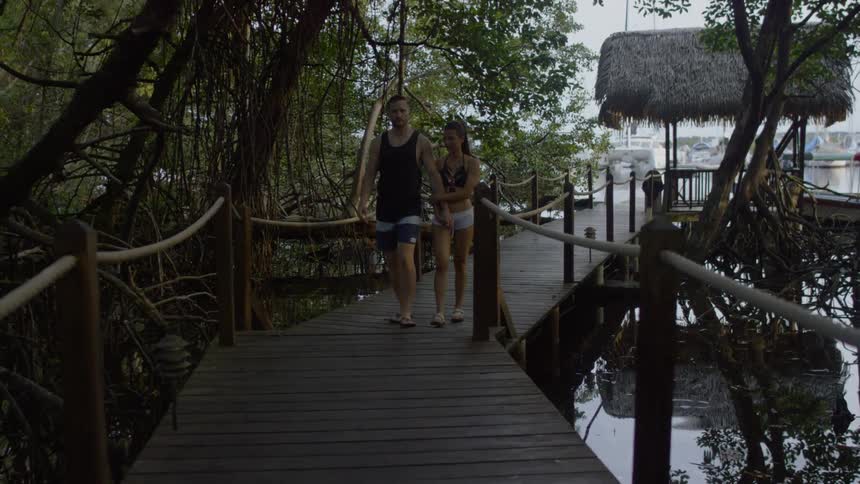 Man and woman hold hands as they walk over a bridge