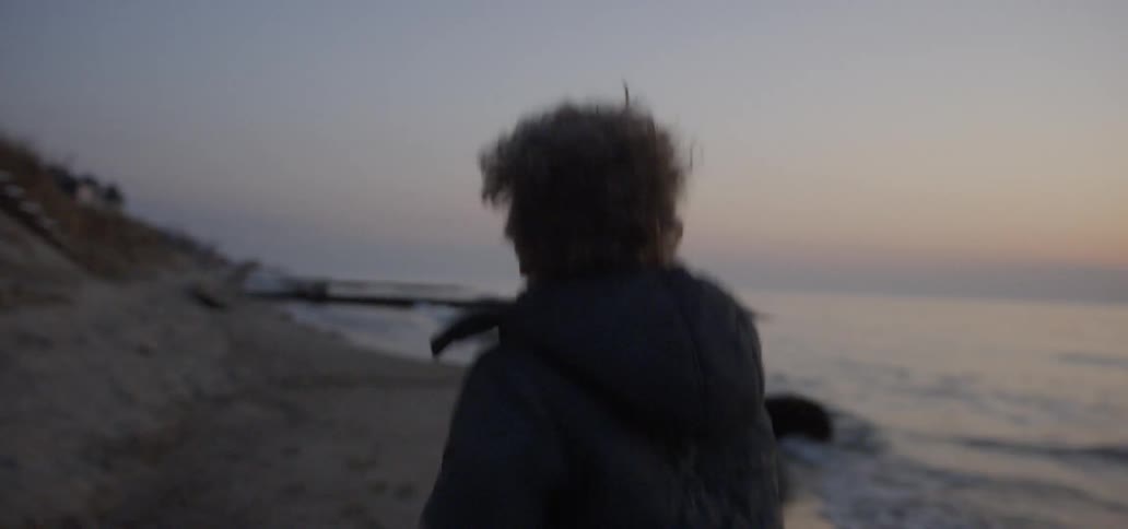 Boy runs on a beach at sunset