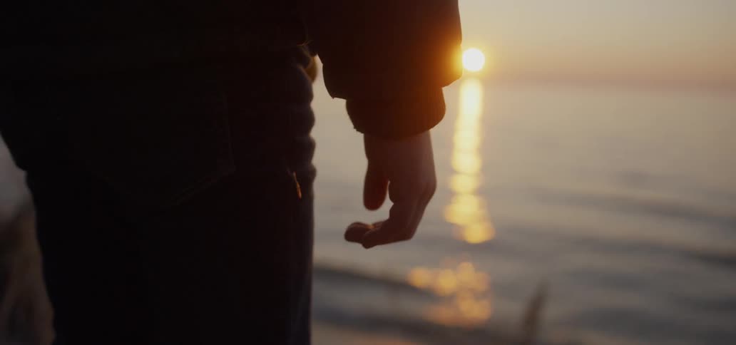 Boy stands on a beach at sunset