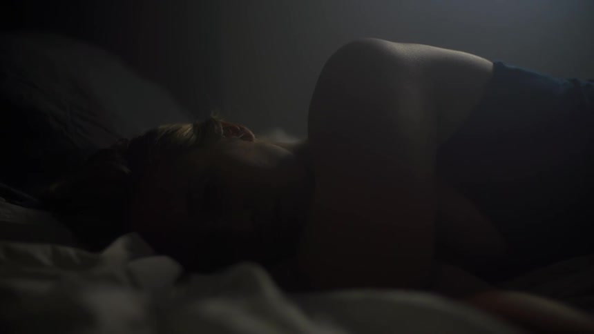 A blonde woman lying on her side in a bed