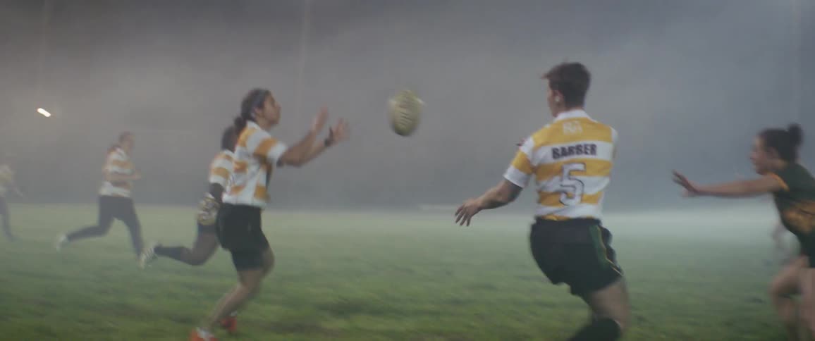 Athletes play rugby football on a foggy field at night