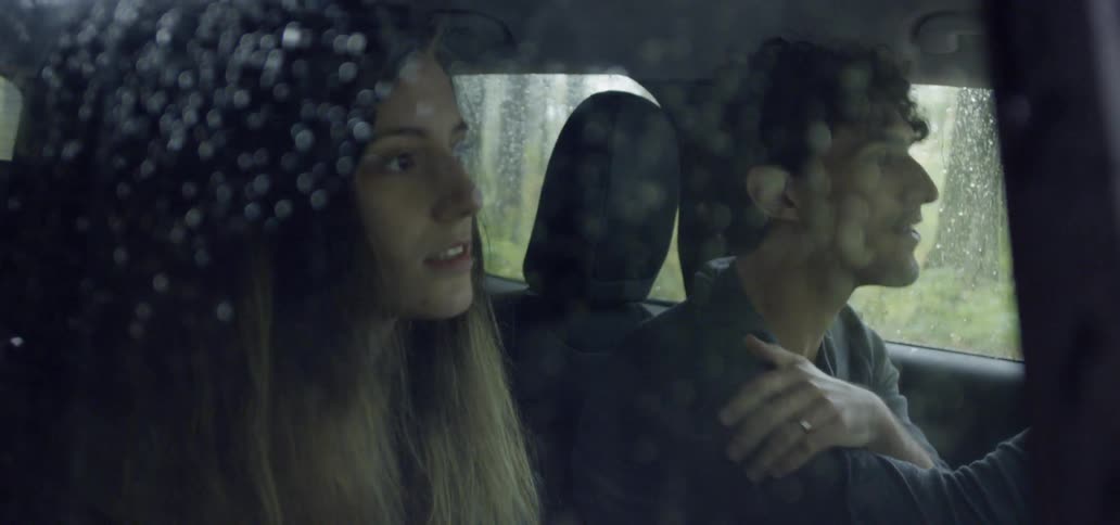 A man and woman drive in the rain