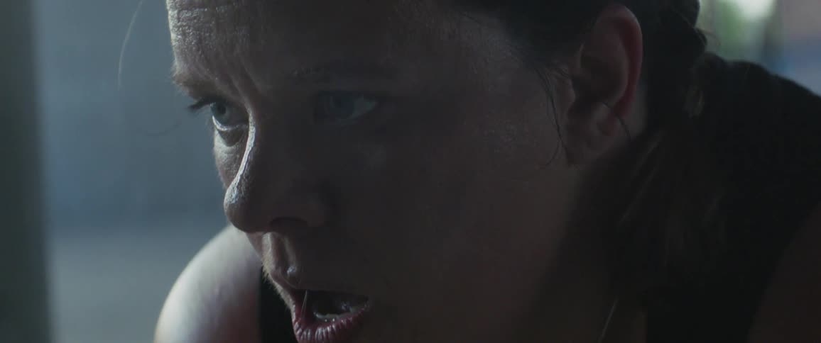 Sweat is dripping off a woman's nose as she breathes heavily inside in daylight