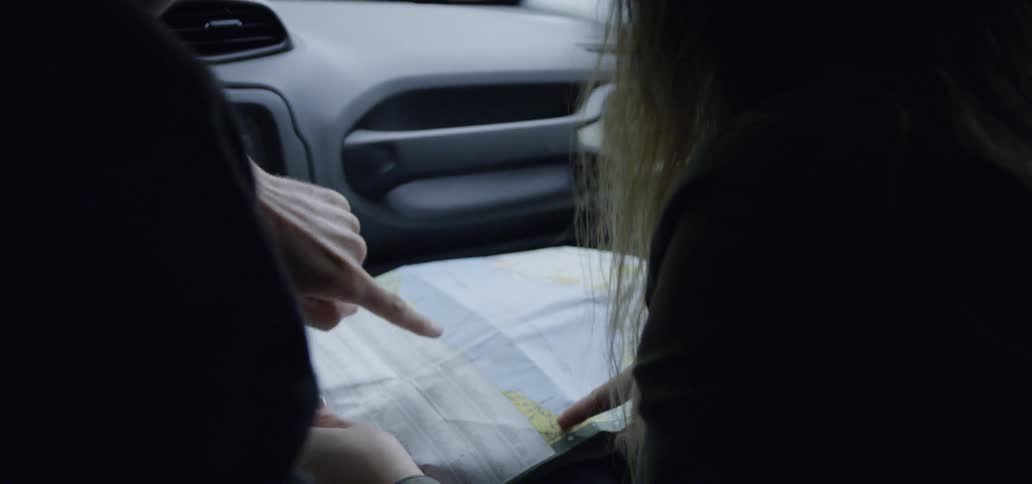 A man and woman look at a road map while sitting in their car