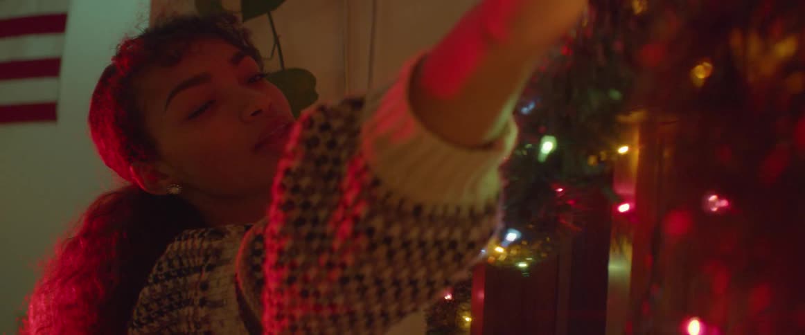 A woman stretches as she hangs lit garland