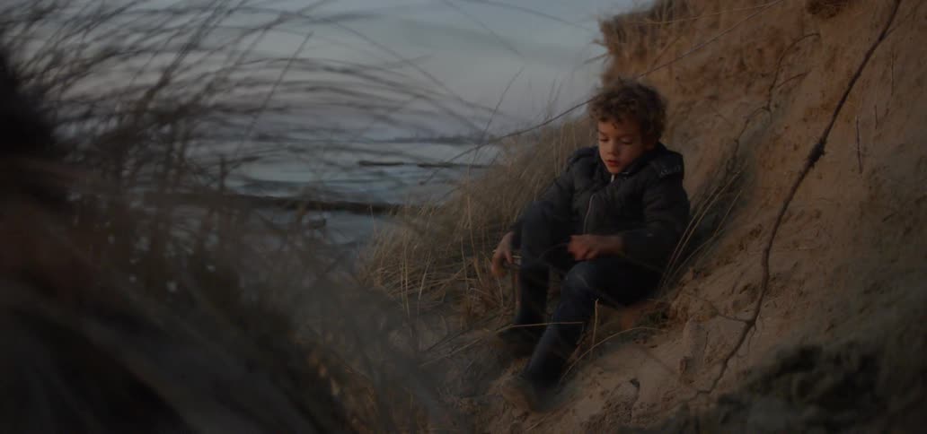 The boy on the hill puts on boots and walks off