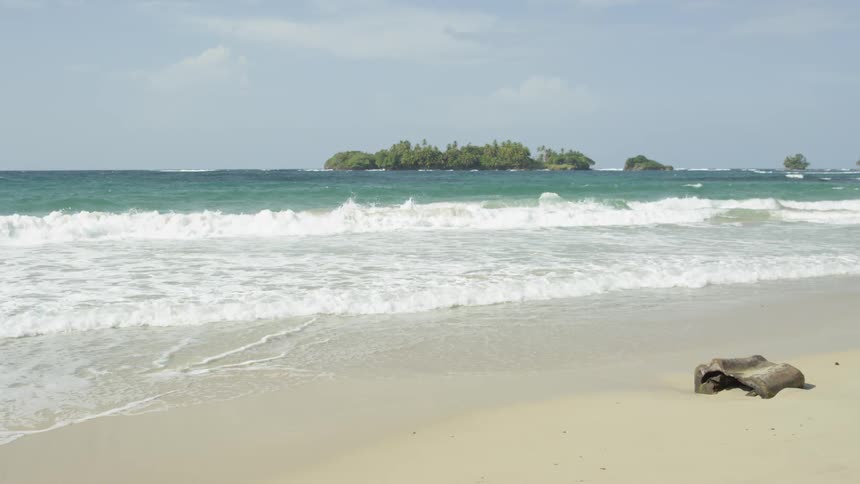 Ocean waves come to shore on a beach on a sunny day