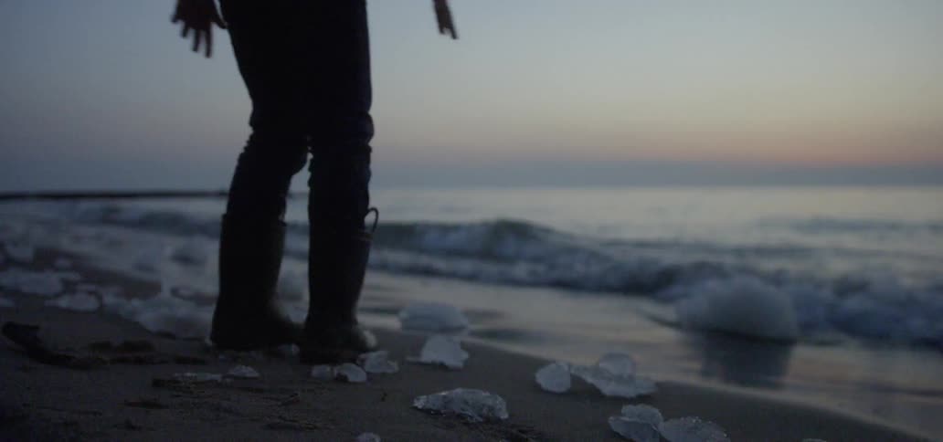 Child throws rocks into the lake as he runs down the beach