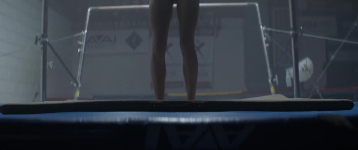 Woman jumps and lands on a mat in a gym