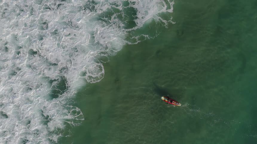 A small row boat travels through an ocean