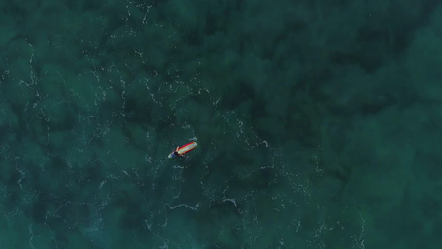 A person is sitting on their surfboard in the water