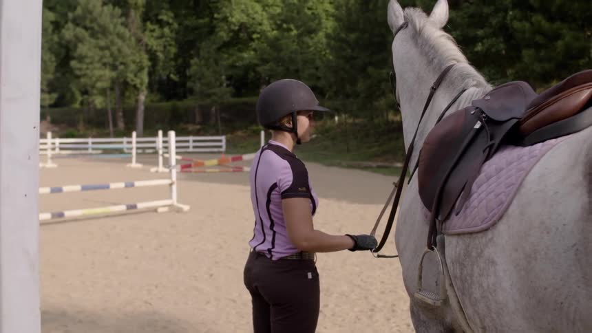 A woman in a pink shirt holds her horses bridle