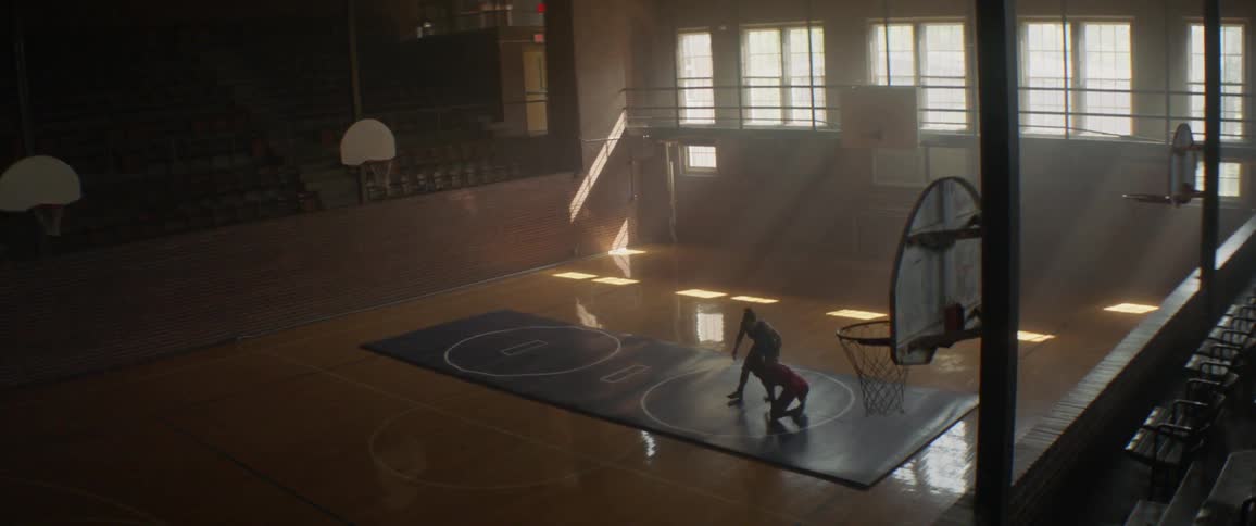 Two women wrestle on a large mat in a gym