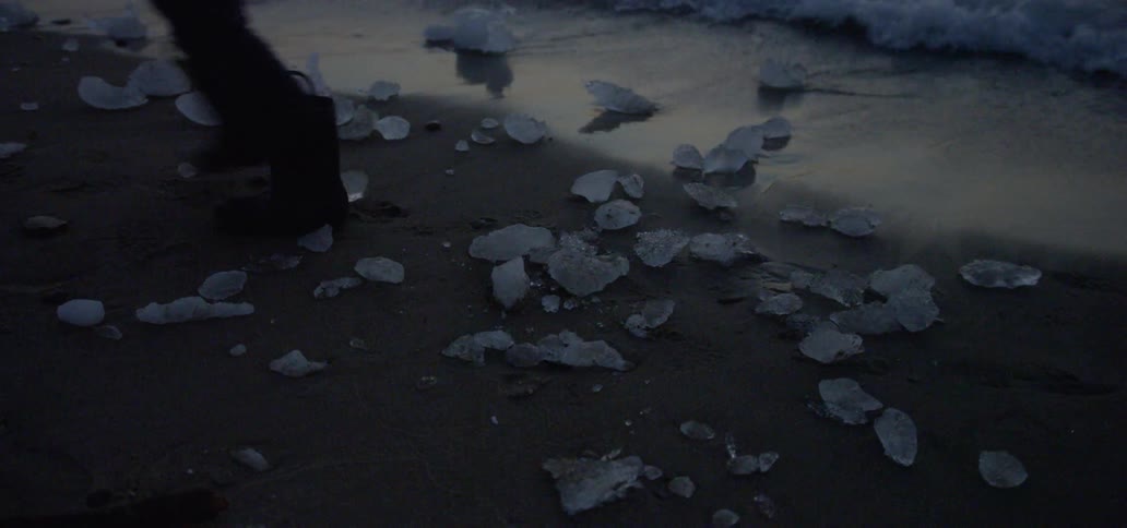 A person walks over the ice near the shore