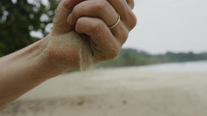 The person drops sand in the wind