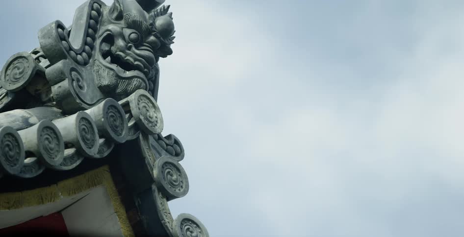Statue sits on a roof of a building under a blue sky